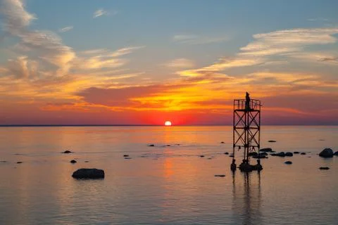 Sunset over sea with magic installation of black monk on the tower Stock Photos