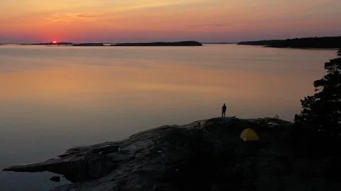 Sunset over the sea with a man walking on the shore Video stock 124385375