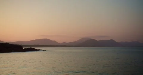 Sunset Over the Sea With Mountains in Background Stock Footage 247462112