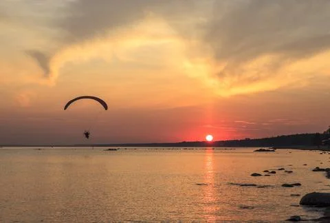 Sunset over the sea. Reflection of the sun in water. Silhouette of paraglider Stock Photos