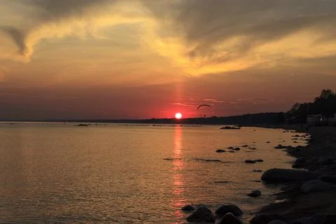 Sunset over the sea. Reflection of the sun in water. Silhouette of paraglider Stock Photos