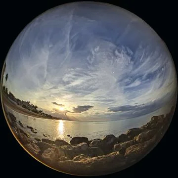 Sunset over the sea with sun rays and dramatic clouds captured from a wide .. Foto stock