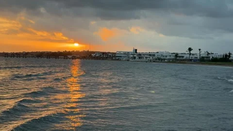 Sunset over seaside town with dramatic clouds reflecting on water surface, .. Stock Footage 336272904