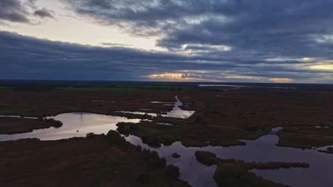Sunset over serene wetlands with reflections glowing under a painted sky in the Stock Footage 321735878