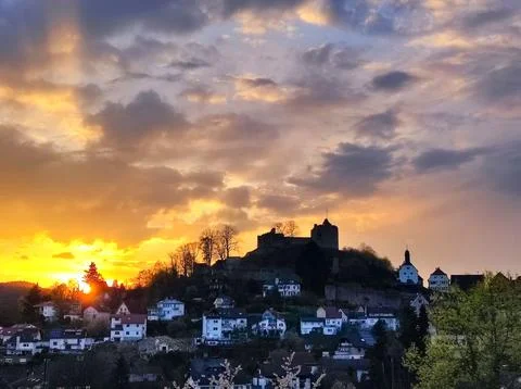 Sunset over a small town with a castle on a hill and clouds in the sky Stock Photos