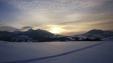 Sunset over a snowy hilly rural landscape.Ski track in snow , transition from Stock Footage 233445442