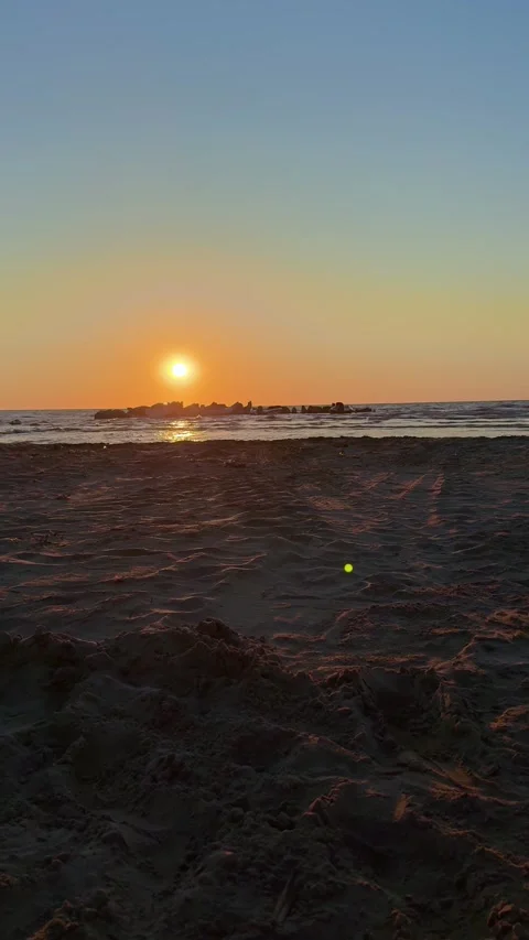 Sunset over tranquil beach with golden sky and calm sea Stock Footage 311831164