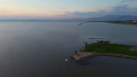 Sunset over a tranquil lake with people on a small peninsula Stock Footage 332301612