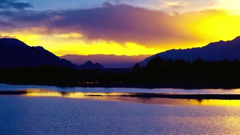 Sunset over a tranquil lake reflecting mountains and colorful sky Stock Footage 311817647