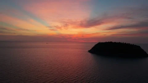 Sunset over tranquil ocean with island silhouette and colorful sky hues Stock Footage 336913440
