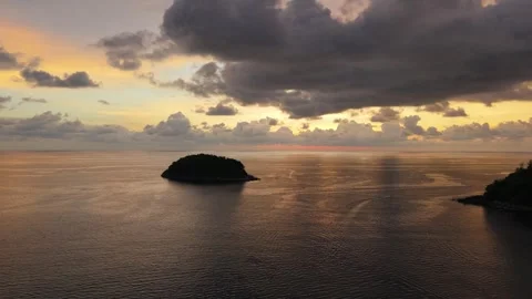 Sunset over tranquil ocean with island silhouette and dramatic clouds Stock Footage 342332311