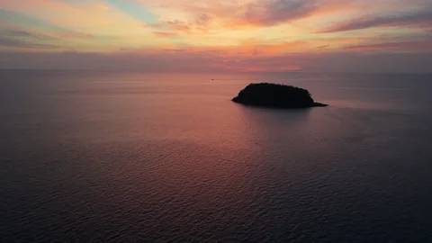 Sunset over tranquil ocean waters with island silhouette in the distance Stock Footage 336926721