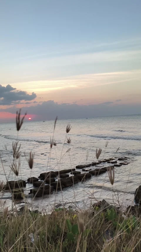 Sunset over Tropical Beach with Waves and Seawall Vertical Stock Footage 340489829