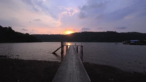 Sunset over tropical white sand beach with pier, distant hills and ocean Stock Footage 332063700