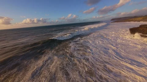 Sunset over turbulent sea, waves breaking on rugged shore Video stock 344550410