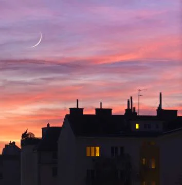Sunset over urban rooftops with lights from some home windows. Photos