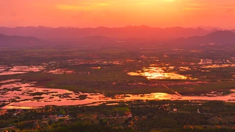 Sunset over valley with glowing reflections in water and dramatic mountains Stock Footage 320286945