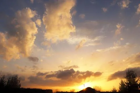 Sunset over the village. Dramatic coloring of the evening sky with cumulus cl Stock Photos
