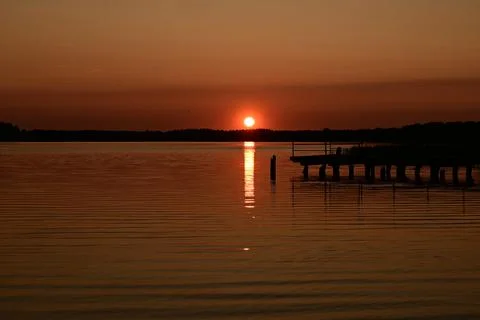 Sunset over water and dock in evening light Stock Photos