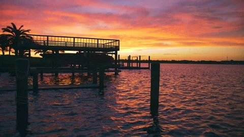 Sunset over water and docks with palm tree 스톡 동영상 96309988