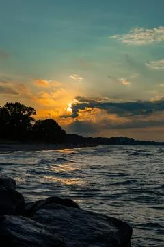 Sunset over the water at the beach with clouds and waves during a summer ev.. Stock Photos