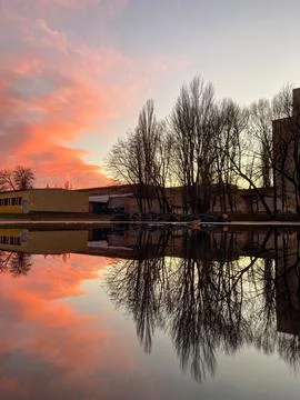 Sunset over the water with reflection of trees and buildings in a quiet loc.. Stock Photos
