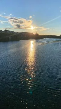 Sunset over water reflects light while clouds fill the sky near a peaceful .. Stock Photos