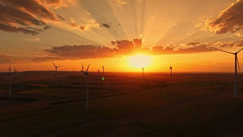 Sunset over wind turbines in open fields with rays of sunlight shining through Stock Footage 344131864