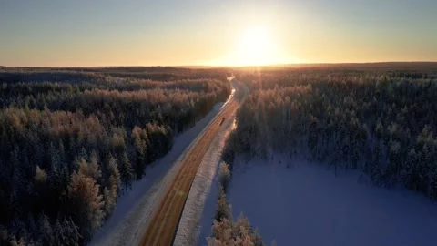 Sunset over winter forest and a road with a car driving towards the sun. Stock Footage 169335154
