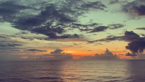 The sunset paints the ocean horizon with warm colors and dramatic clouds Stock Footage 338282767