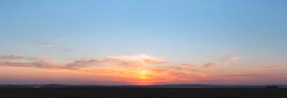 Sunset panorama with raspberry clouds on a blue sky background Stock Photos