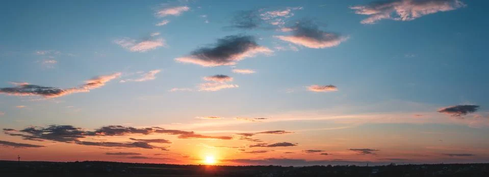 Sunset panorama with raspberry clouds over a small town Stock Photos