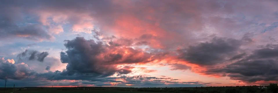Sunset panorama with raspberry clouds over a small town Stock Photos