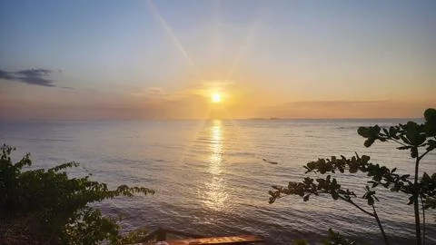 Sunset on a paradisiacal beach with the sun's rays spread across the sky and  Stock-Fotos