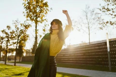 At sunset in the park the blower throwing on one shoulder coat raised her hand Stock Photos