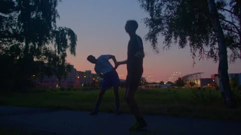 Sunset park exercise where man supports woman during stretching routine Stock Footage 325071611