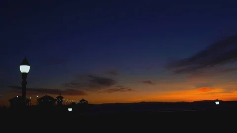 Sunset at the pier with lights and people walking by, 4K Stock Footage 101002465
