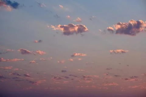 Sunset with pink and orange clouds in the sky, as the sun's rays gently pass Stock Photos