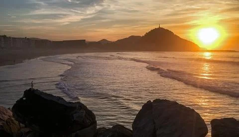 Sunset at Playa de Gros with Monte Urgul and waves San Sebastian Spain 스톡 사진