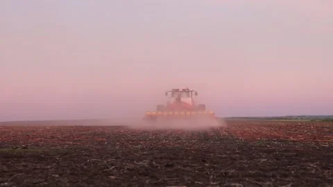 At sunset a powerful tractor sows the spring crops 動画素材 239973417