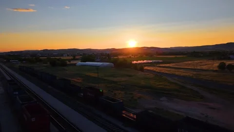 Sunset Pullback Revealing Freight Train, Greenhouses and Rural Farmland Stock Footage 340515200
