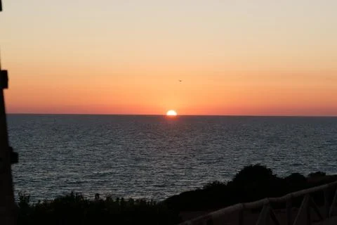 Sunset on the quiet ocean creating an orange and pink sky Stock Photos