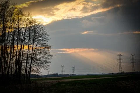 Sunset - rays breaking through the clouds. In the background, the power gri.. Stock Photos