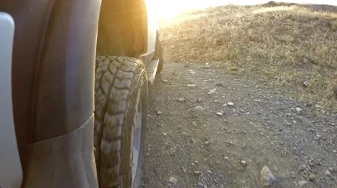Sunset rays falling on a jeep riding on a bad mountainous road with great view Stock Footage 62911827
