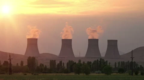 Sunset rays over cooling towers of nuclear power plant emitting steam Stock Footage