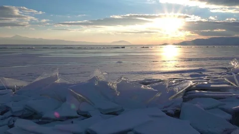 Sunset rays over small icebergs and icicles in the frozen lake Stock Footage 73299239