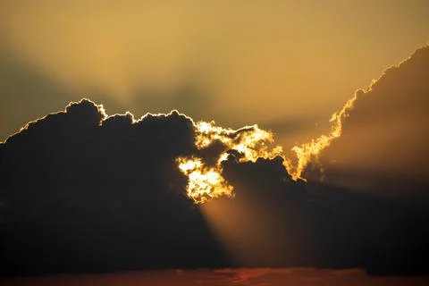 The sunset rays of the sun make their way through the clouds Stock Photos