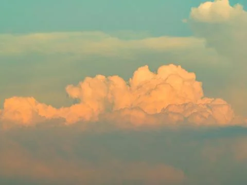 Sunset red glow on billowing cloud through atmospheric haze Stock Photos