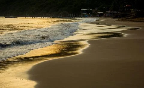 The sunset is reflected in the water arriving at a beach Stock Photos