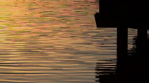 Sunset reflecting in lake waters beneath the silhouette of a dock. Stock Footage 119347272